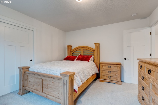 bedroom with light colored carpet and a textured ceiling