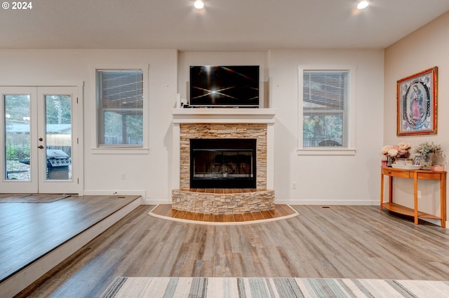 unfurnished living room featuring a fireplace, light hardwood / wood-style flooring, and french doors