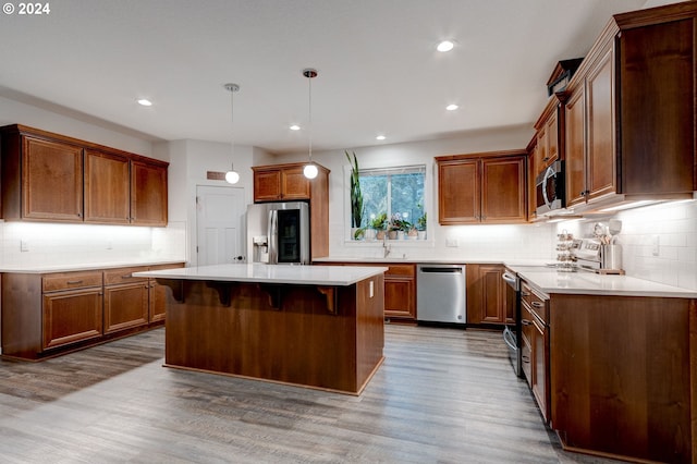 kitchen with decorative light fixtures, a center island, wood-type flooring, and stainless steel appliances