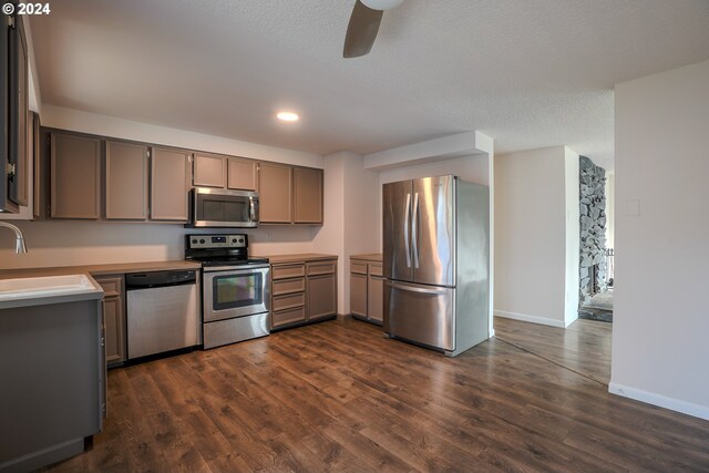 kitchen with gray cabinetry, sink, dark wood-type flooring, stainless steel appliances, and a textured ceiling