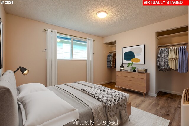 bedroom with hardwood / wood-style floors, a textured ceiling, and a closet