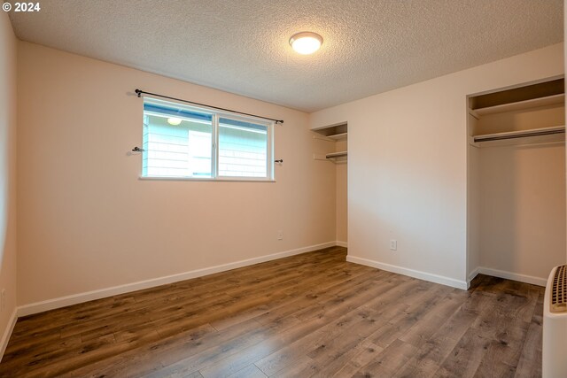 unfurnished bedroom with dark hardwood / wood-style flooring and a textured ceiling