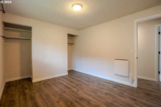 unfurnished bedroom featuring a textured ceiling, dark hardwood / wood-style floors, and heating unit