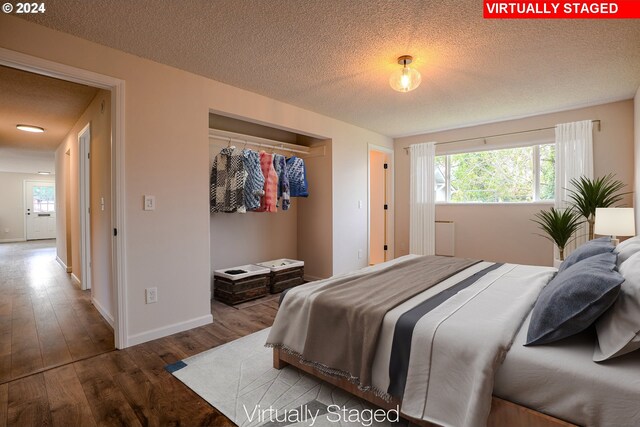 bedroom with a textured ceiling, hardwood / wood-style flooring, and a closet