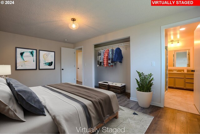 bedroom featuring a textured ceiling, sink, hardwood / wood-style flooring, connected bathroom, and a closet