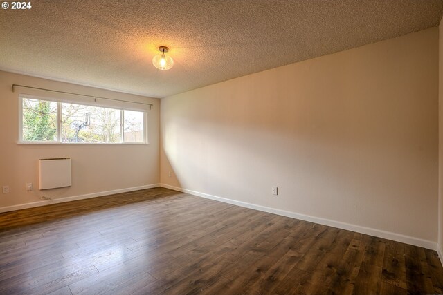 spare room with a textured ceiling and dark hardwood / wood-style floors