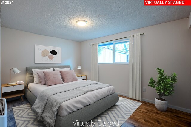 bedroom featuring a textured ceiling and dark hardwood / wood-style floors