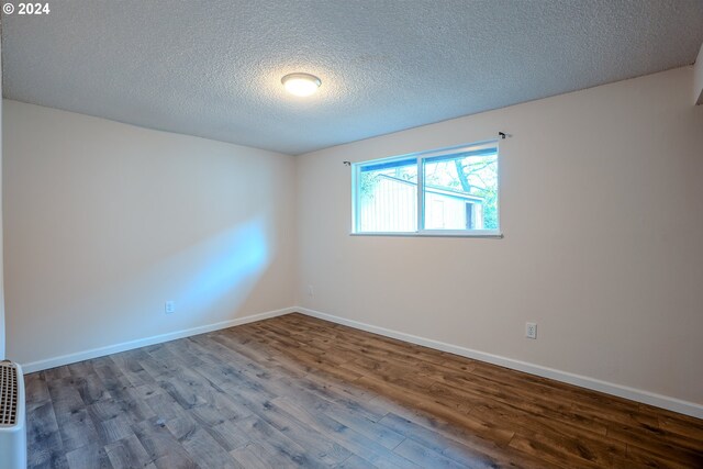 unfurnished room with hardwood / wood-style flooring and a textured ceiling