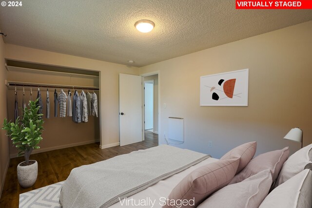 bedroom with a textured ceiling, dark wood-type flooring, and a closet