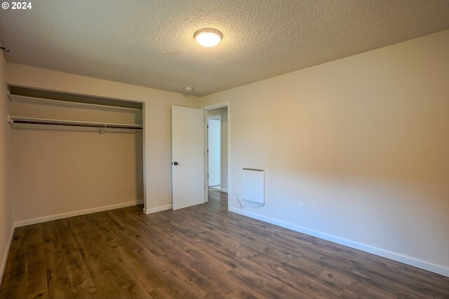 unfurnished bedroom featuring a textured ceiling, a closet, and dark wood-type flooring