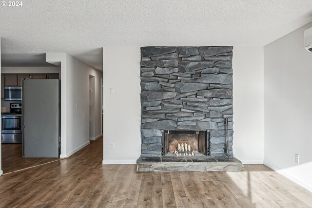 unfurnished living room featuring a fireplace, a textured ceiling, and hardwood / wood-style flooring