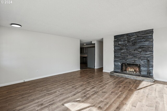 unfurnished living room with a fireplace, a textured ceiling, and hardwood / wood-style flooring