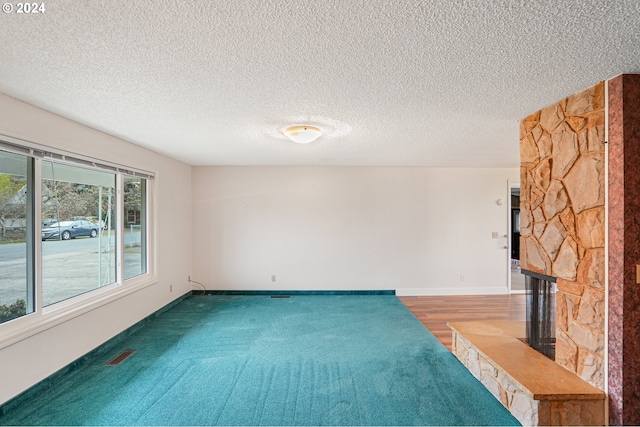 unfurnished room featuring a fireplace, a textured ceiling, and dark hardwood / wood-style flooring