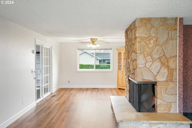 unfurnished living room featuring a fireplace, ceiling fan, hardwood / wood-style floors, and a textured ceiling