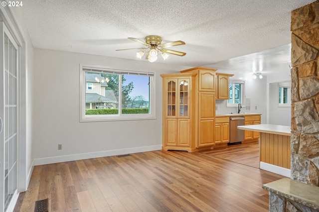 kitchen featuring ceiling fan, dishwasher, a textured ceiling, and light hardwood / wood-style flooring