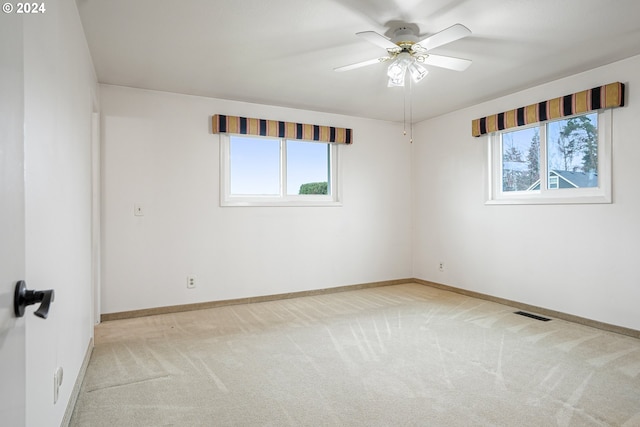 empty room featuring ceiling fan and light colored carpet