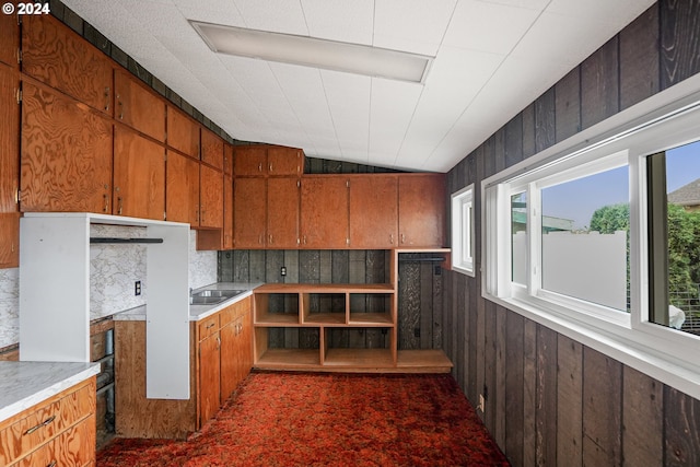 kitchen featuring lofted ceiling, wooden walls, and backsplash