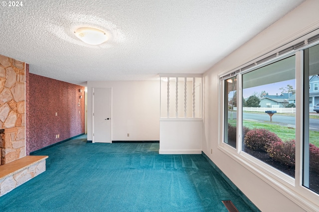 unfurnished room with dark colored carpet, a textured ceiling, and a fireplace