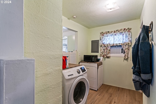 clothes washing area featuring light hardwood / wood-style flooring, a textured ceiling, a healthy amount of sunlight, and separate washer and dryer