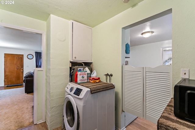 clothes washing area with light hardwood / wood-style floors, washer / clothes dryer, and a textured ceiling