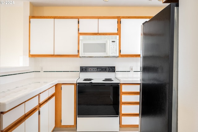 kitchen with tile counters, white appliances, tasteful backsplash, and white cabinetry