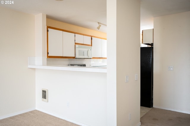 kitchen with rail lighting, tasteful backsplash, light colored carpet, and white cabinets