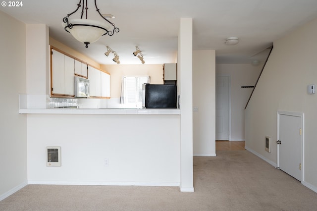 kitchen featuring white cabinetry, light carpet, black fridge, and track lighting