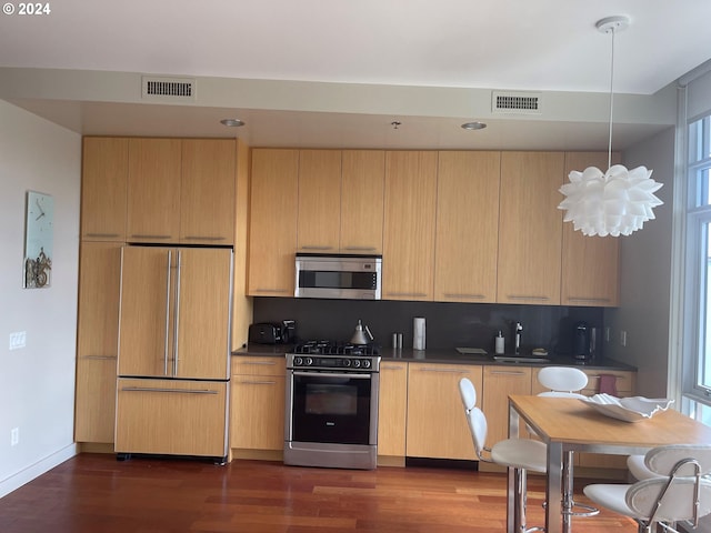 kitchen with light brown cabinets, tasteful backsplash, a notable chandelier, dark hardwood / wood-style flooring, and stainless steel appliances