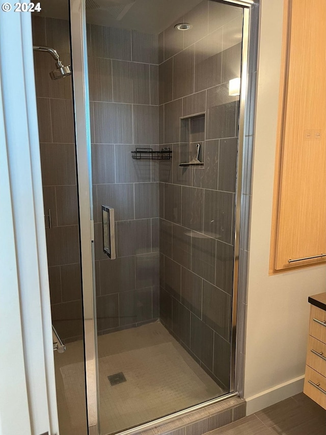 bathroom featuring vanity, hardwood / wood-style flooring, and a shower with shower door