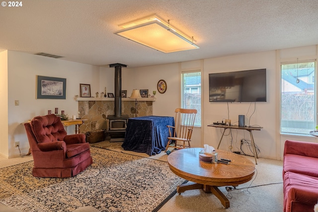 living room featuring carpet flooring, a wood stove, and a textured ceiling