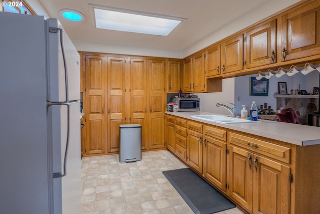 kitchen with white fridge, kitchen peninsula, and sink