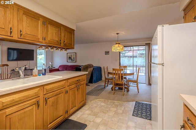 kitchen with pendant lighting, white fridge, a wealth of natural light, and sink