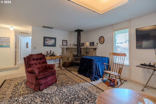 living room featuring a wood stove, a textured ceiling, and light carpet