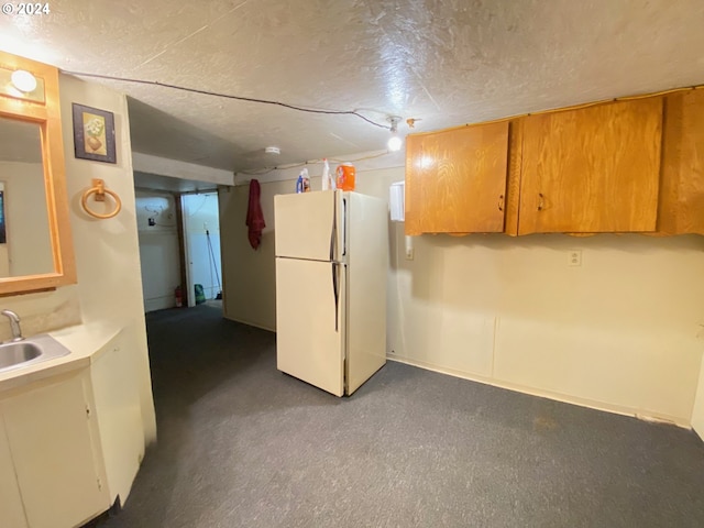 kitchen with sink, white fridge, carpet flooring, and a textured ceiling