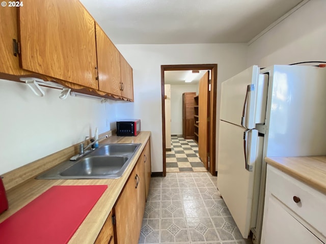 kitchen featuring sink, light tile patterned floors, and white refrigerator