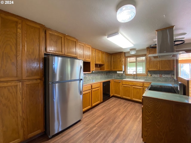 kitchen with dishwasher, sink, island range hood, stainless steel fridge, and hardwood / wood-style flooring