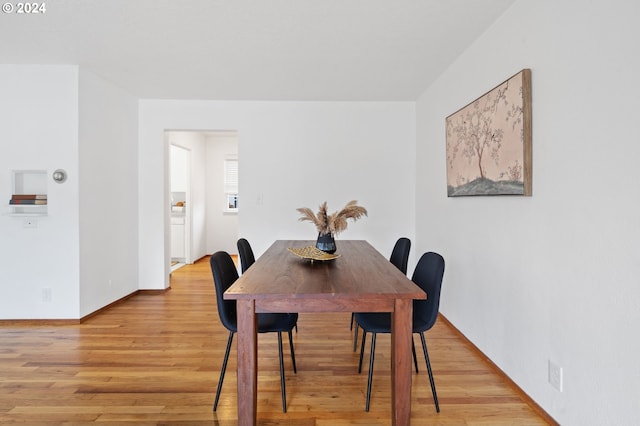 dining area with light wood-type flooring and baseboards