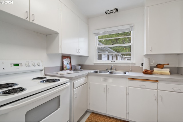 kitchen with white range with electric cooktop, white cabinets, visible vents, light countertops, and a sink