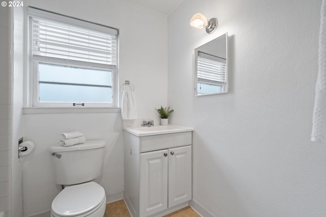 bathroom with toilet, vanity, and baseboards