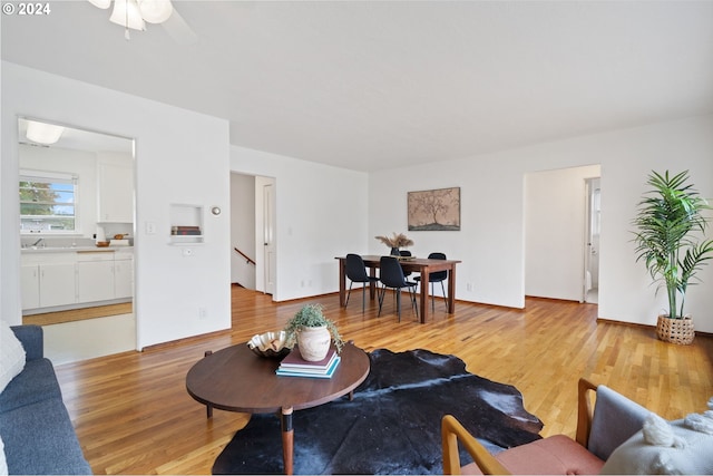 living room with light hardwood / wood-style flooring, ceiling fan, and sink