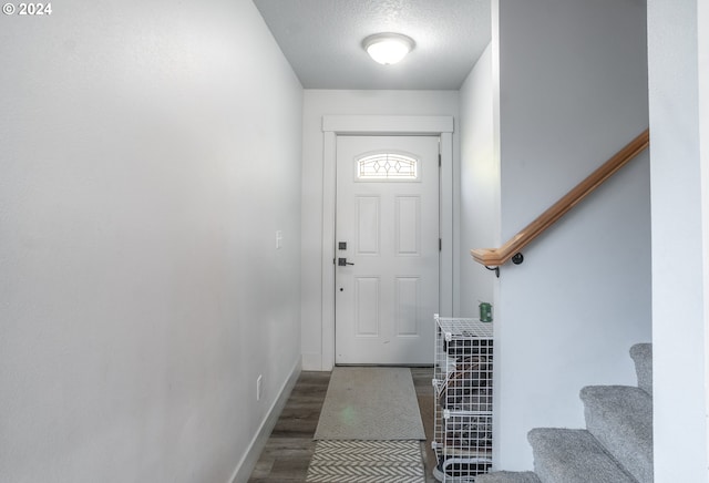 doorway to outside with dark hardwood / wood-style flooring and a textured ceiling