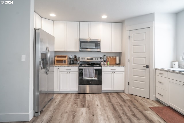 kitchen featuring appliances with stainless steel finishes, light hardwood / wood-style floors, white cabinetry, and light stone countertops