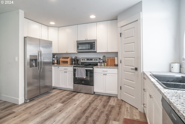 kitchen with light hardwood / wood-style flooring, stainless steel appliances, and white cabinetry