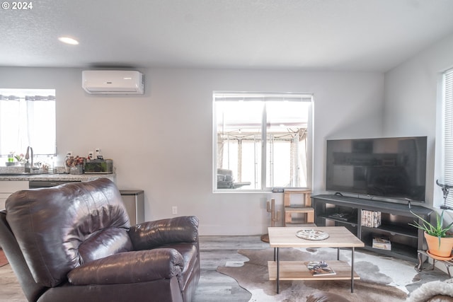 living room featuring sink, light hardwood / wood-style flooring, a healthy amount of sunlight, and a wall unit AC