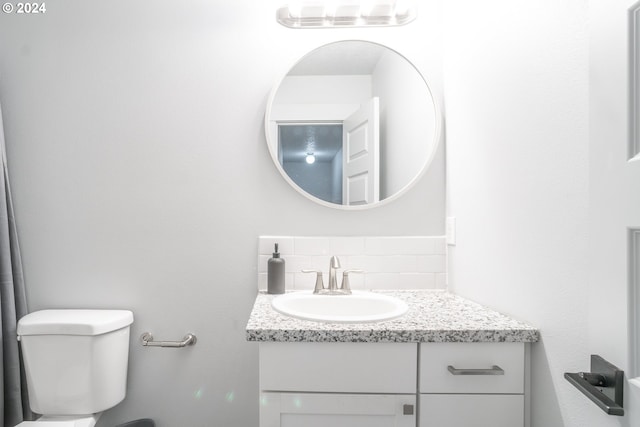 bathroom featuring tasteful backsplash, toilet, and vanity