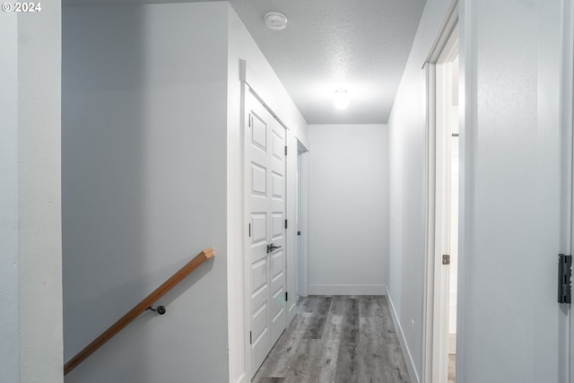 hallway with light hardwood / wood-style floors and a textured ceiling