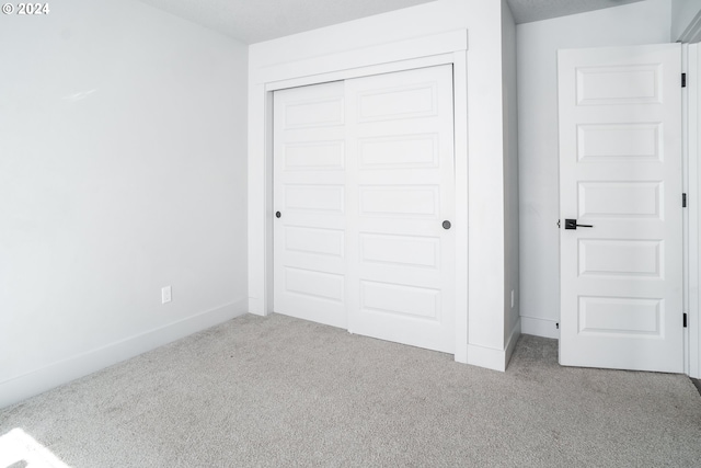 unfurnished bedroom featuring a closet and light carpet