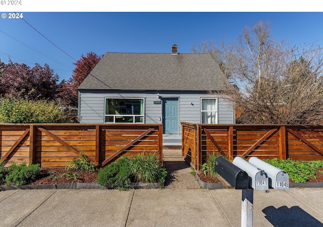 view of front of home featuring roof with shingles and fence