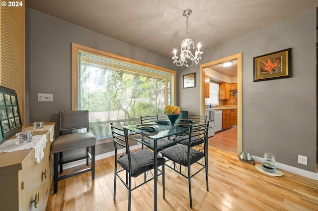 dining area with light hardwood / wood-style floors and an inviting chandelier