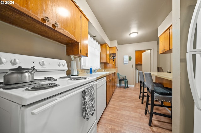 kitchen with sink, white appliances, and light wood-type flooring